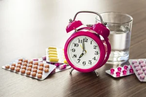 قرص فشار خون کنار ساعت و لیوان آب برای نمایش زمان مصرف دارو